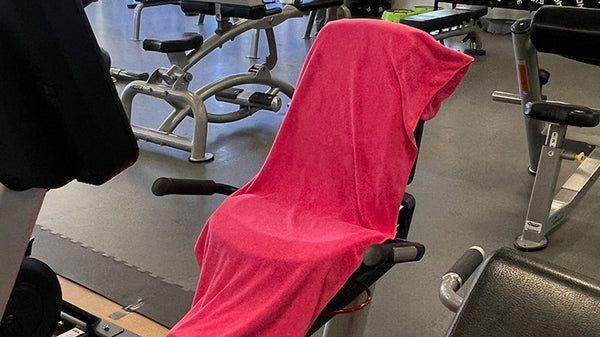 Custom FITZEN microfiber gym towel draped over a weight bench in a gym setting